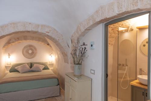 阿尔贝罗贝洛Trulli Magheia的一间卧室配有一张床,浴室设有水槽