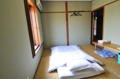 Omitamaビジネスホテル六号的客房设有带白色床单的床和窗户。