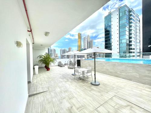巴拿马城Hotel Mio Panamá的大楼内带游泳池和遮阳伞的阳台