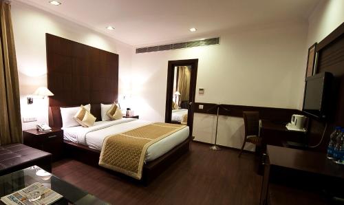 新德里Divine Paradise Tavisha的配有一张床和一张书桌的酒店客房