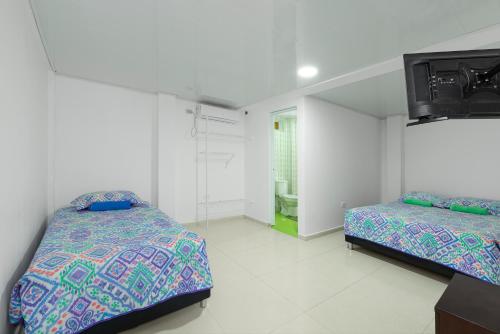 圣安德烈斯La isla inn的一间卧室设有两张床,墙上配有电视。