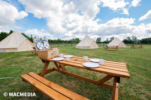 温彻斯特Bell tent glamping at Marwell Resort的野外野餐桌,带盘子和帐篷