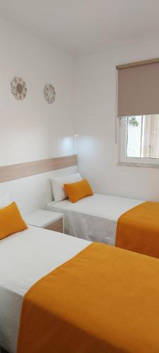 波尔蒂芒CASA BIA的带3张床、橙色床单和窗户的客房