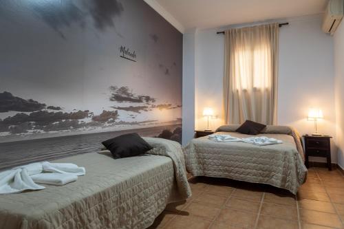 埃尔罗西奥Alojamiento Rural El Sombrero的一间卧室配有两张带毛巾的床