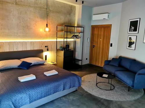 格涅兹诺Apartamenty Dobry Browar的一间卧室配有蓝色的床和蓝色的沙发