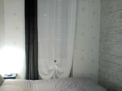 第戎Le petit Saint Bernard的一间卧室配有一张带白色窗帘的床