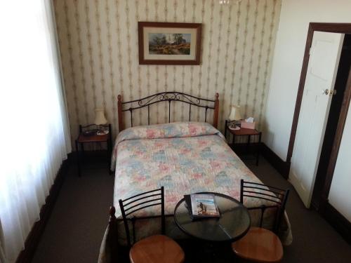 沃拉鲁松本汽车旅馆的一间小卧室,配有一张床和两张桌子