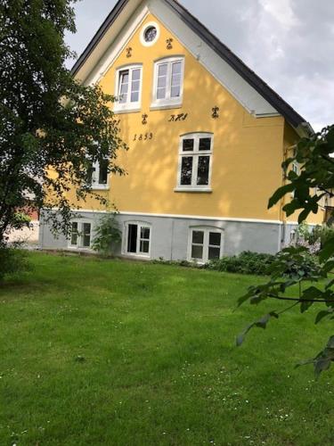 欧登塞Allesø Gl. sognefoged gård的一座黄色的大房子,前面有一座院子