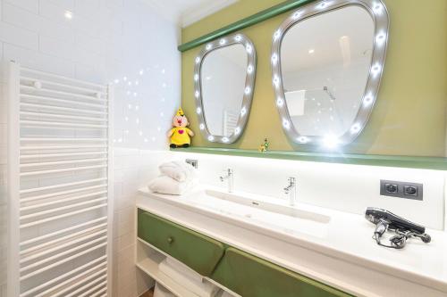 德帕内Plopsa Hotel的一间带水槽和两面镜子的浴室