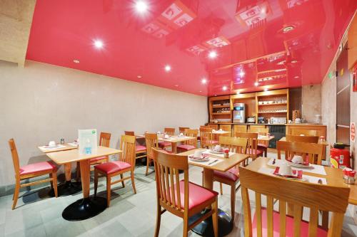 巴黎格兰德酒店的餐厅设有木桌和椅子,拥有红色的天花板。