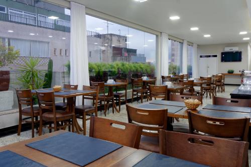 圣保罗Fênix Hotel Bom Retiro的餐厅设有木桌、椅子和窗户。