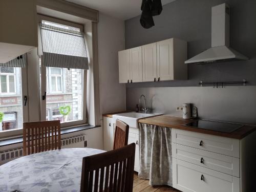 杜柏Logies l'Epicerie de Durbuy appartement的厨房配有白色橱柜和桌椅
