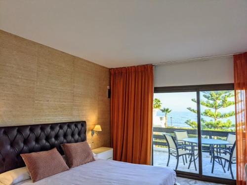马贝拉珊瑚海滩公寓式酒店的一间卧室配有一张床,阳台配有桌子