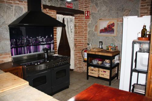 贝拉约斯Casa Rural Puerta de Castilla的一间带炉灶的厨房和一台墙上的电视