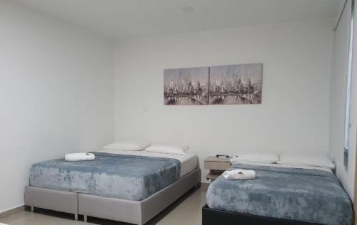 La PazHOTEL SAN PEDRO的一间卧室设有两张床,墙上挂着一幅画