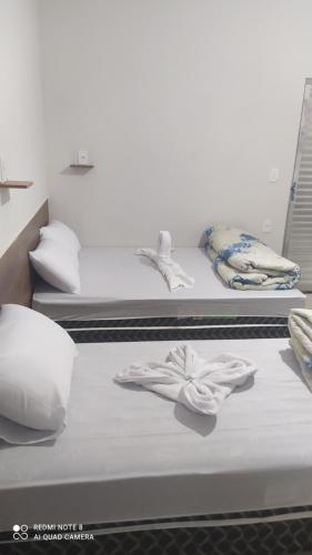 阿帕雷西达Pousada Quarto completo ar,wi fi e garagem gratuita的两张带白色床单和毛巾的床