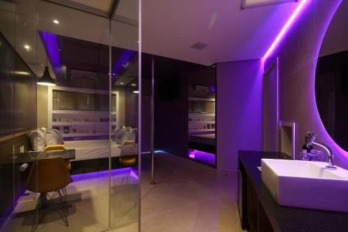 皮拉西卡巴Oasis Motel的一间带水槽和紫色照明的浴室