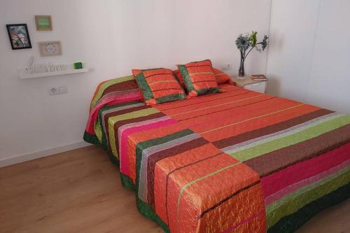 FortalenyAitana的一间卧室配有一张带彩色毯子和枕头的床。