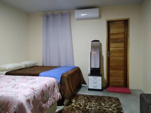 蒙蒂达斯加梅莱拉斯Chalés Serra Monte的一间卧室配有两张床、一台电视和一扇门