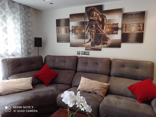 马贝拉Amplio apartamento Marbella的客厅配有棕色沙发和一些绘画作品