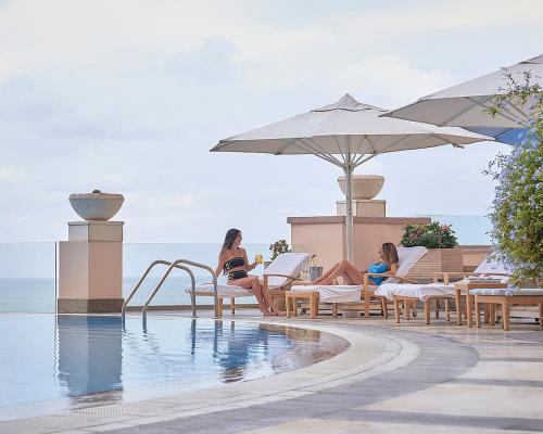 亚历山大亚历山大港圣斯特凡诺四季酒店的两个女人坐在游泳池旁的椅子上
