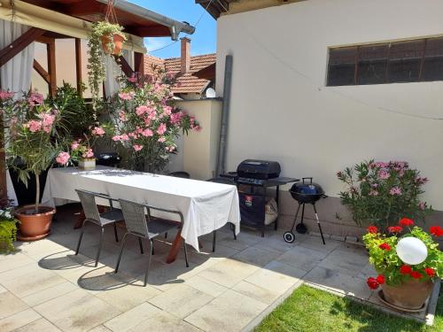 久洛Aranka Apartman的鲜花庭院里的白色桌子和椅子