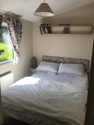 布莱克浦Stunning deluxe 3 bedroomed caravan with CH, DG and decking.的一间小房间的卧室,配有一张床铺
