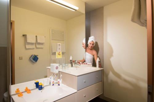 奎德林堡哈茨家庭俱乐部假日公园的站在镜子前的浴室里的人