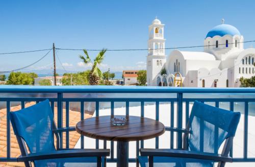 斯卡拉Saronis Hotel Agistri - Adults Only的一个带清真寺的阳台,配有一张桌子和两把椅子