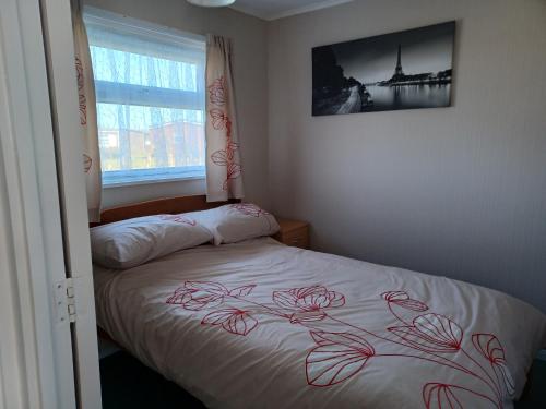 大雅茅斯alicias chalets的一间卧室配有一张带红色玫瑰床罩的床
