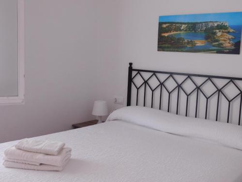 卡拉加尔达纳Apart.Can Pons,con piscina, a 50 de la playa的卧室配有白色的床和2条毛巾