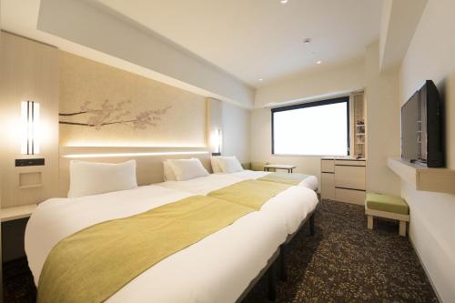 东京Hotel Yaenomidori Tokyo的酒店客房设有两张床和电视。