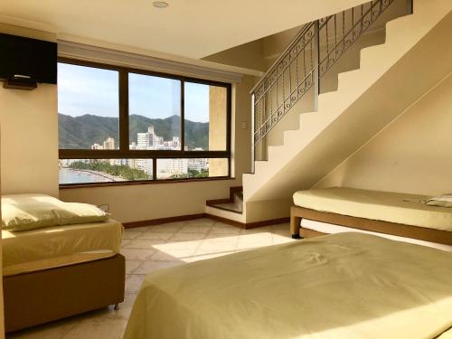 圣玛尔塔Edificio El Peñon del Rodadero的一间带两张床的卧室和一个带窗户的楼梯