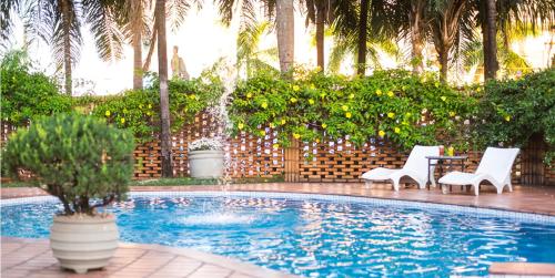 特雷斯拉瓜斯Vila Romana Park Hotel的一个带两把椅子和一张桌子的游泳池以及一个喷泉