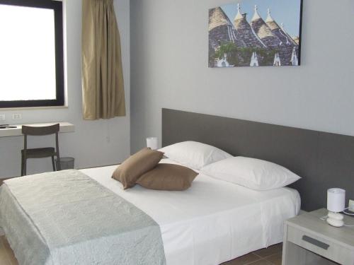特里尼塔波利L'incontro的一间卧室配有带白色床单和枕头的床。