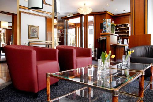 慕尼黑安巴赛德公园酒店的客厅配有红色椅子和玻璃桌