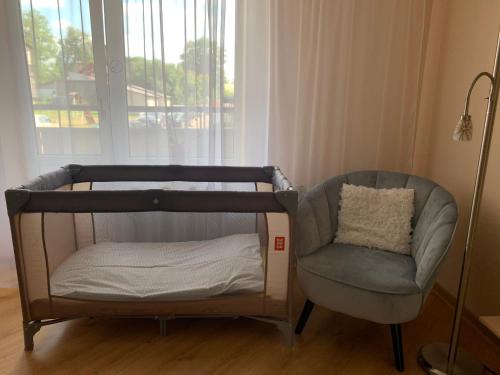阿卢克斯内Apartamenti Bulvāris的窗户房间里一张婴儿床和一把椅子