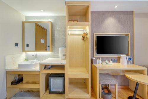 哈尔滨哈尔滨旅悦精品酒店的一间带水槽的浴室和客房内的电视