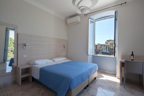 克里日亚Cecio 5 Terre Rooms的白色卧室设有蓝色的床和窗户