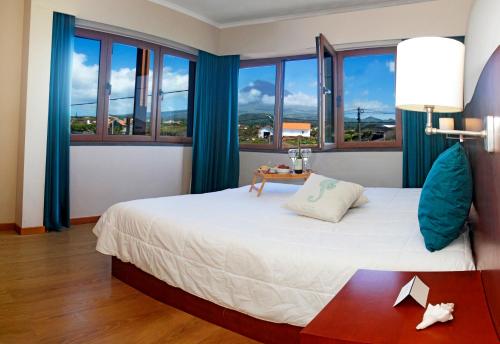 马达莱纳拜亚达巴卡酒店的一间卧室配有一张大床,配有蓝色窗帘和窗户。