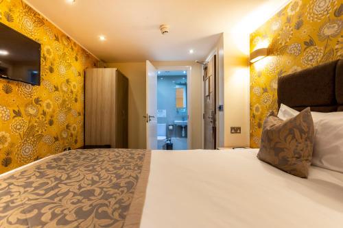 伦敦Hotel Shepherds Bush London的一间卧室设有一张黄色墙壁的大床