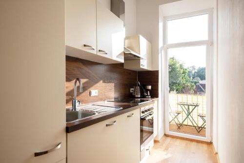 格拉茨格拉茨城市公寓的厨房配有白色橱柜、水槽和窗户。