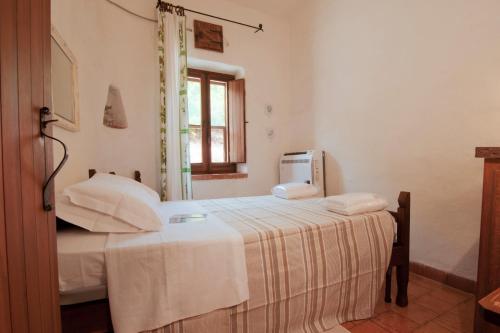 圣乔万尼·迪·希尼斯Villa San Marco - Casa esclusiva nel Sinis的一间卧室配有一张带白色床单的床和一扇窗户。