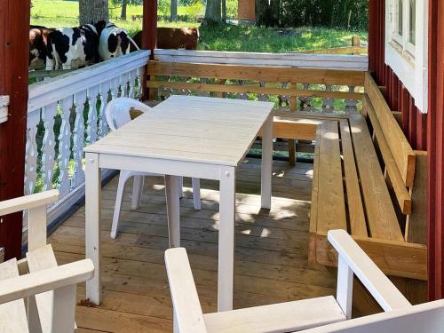 韦特兰达4 person holiday home in VETLANDA的门廊上的白色桌子和椅子,有狗