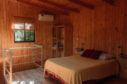 伊瓜苏港Cabaña Oma的小木屋内一间卧室,配有一张床