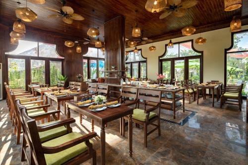 宁平Bai Dinh Riverside Resort & Spa的餐厅设有木桌、椅子和窗户。