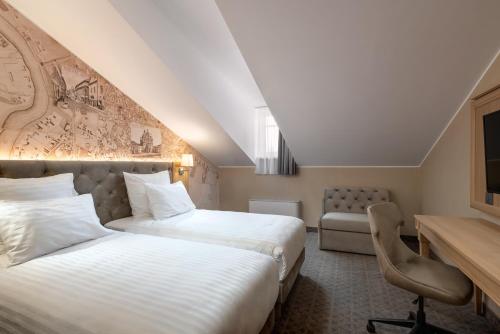 维尔纽斯CALVARY Hotel & Restaurant Vilnius的酒店客房配有两张床和一张书桌