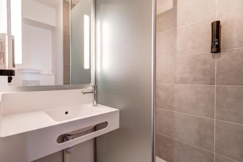马尔利港B&B HOTEL Le Port Marly Saint Germain en Laye的一间带水槽和镜子的浴室