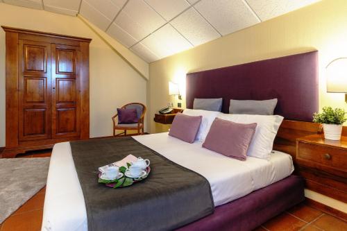 尼科洛西Corsaro Etna Hotel&SPA的一间卧室配有一张大床,上面放着一盘鲜花