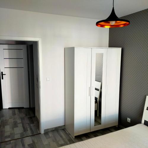 克拉科夫APARTAMENT HELSINKI的一间设有白色橱柜和镜子的客房